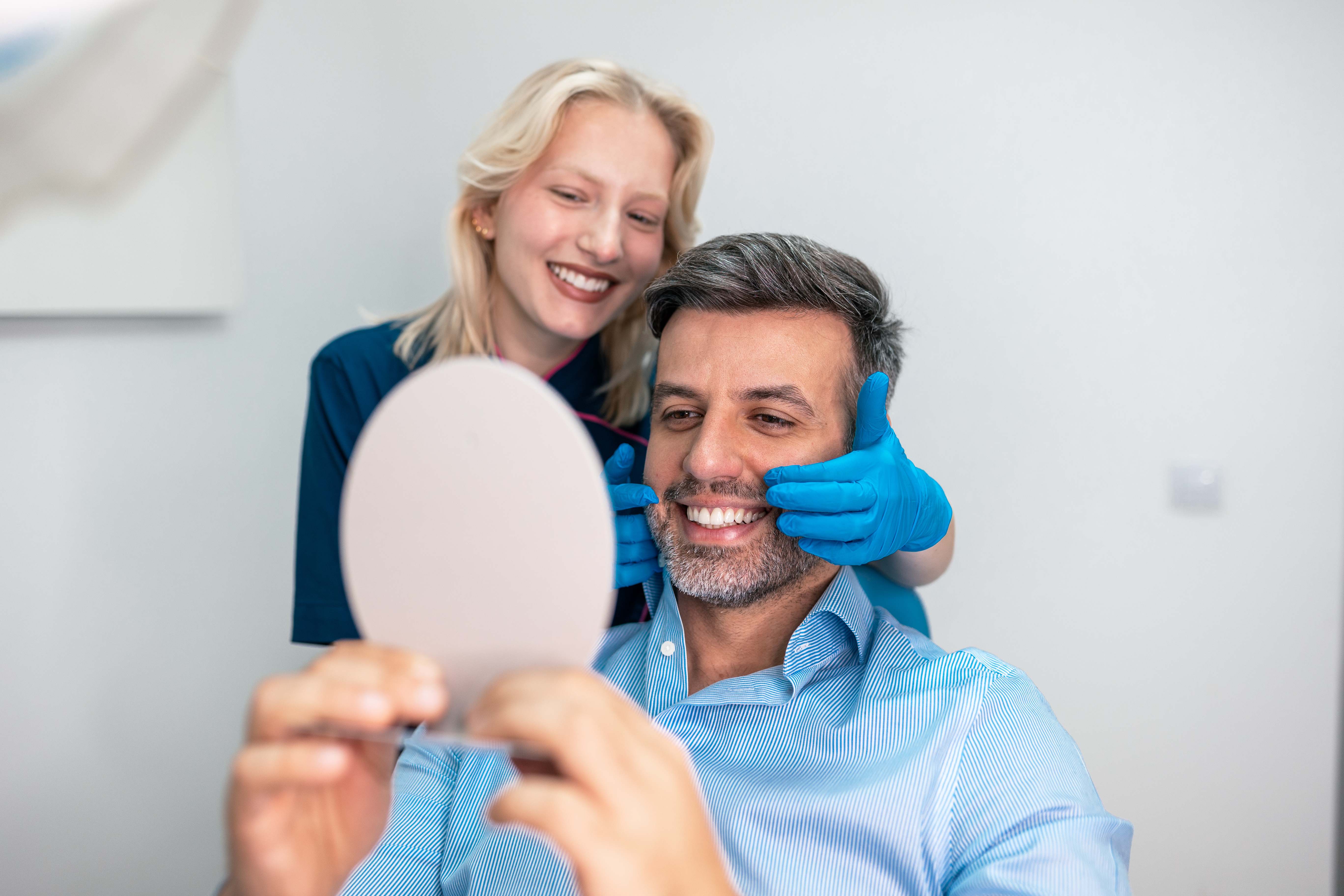 A Terrell Hills Dental patient seeing their finished smile in a mirror in San Antonio, TX